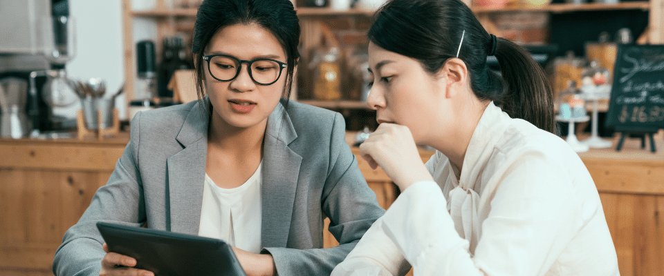 Two women looking at an iPad screen in a cafe