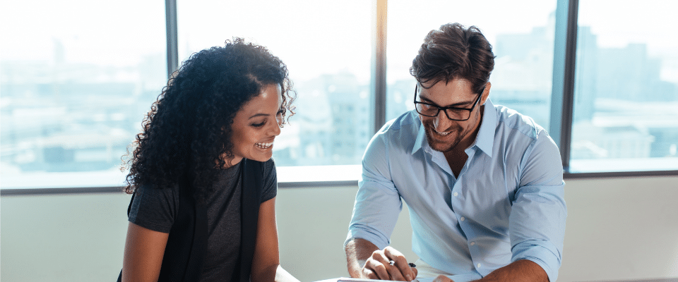 A man and a woman looking over papers in an office.